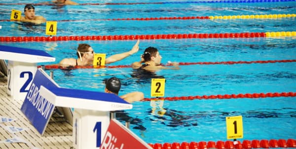 游泳者在游泳比赛的泳道上等着看他们的时间。